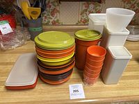 Full view of stacked round containers, small cups, measuring cup, and rectangular containers on a kitchen counter.