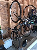 Full bike angled photo showing dark green Liberty Arashi frame hanging in garage with tires and pedals visible.