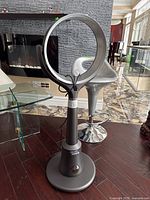 Full view of the standing bladeless floor fan with cylindrical base and ring-shaped top, power cord wrapped around the stand.