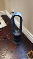 Full view of Dyson Hot + Cold bladeless fan plugged in and standing on wooden floor.