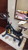Full side view of black and yellow spinning bike on rug in room