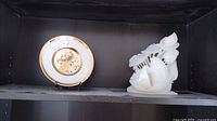 Shelf display showing the white jade carving and the decorative art plate side by side