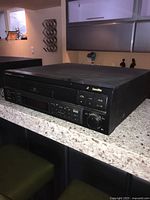 Clear image of the black Pioneer CLD-S201 Laser Disk player with front loading tray on counter.