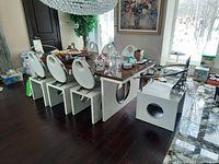 Front left angle view of dining table with eight matching chairs and miscellaneous items on tabletop.