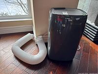 Front view of the alloy gray portable AC with attached white exhaust hose