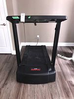 Front view of black Pro-Form treadmill with control panel and EKG grip pulse sensors on handlebars, showing treadmill structure and running belt.