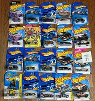 Overhead photo showing 20 assorted Hot Wheels cars in original packaging laid out on floor.