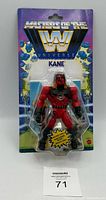 Front view of Masters of the WWE Universe KANE action figure in sealed packaging. Figure is red and black armored with muscular design, visible through clear blister pack. Package features colorful background with WWE Universe branding and character name.