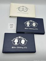 Two dark blue Silver Wedding 1972 albums and one white Royal Wedding 1973 album stacked, clearly showing embossed text and silhouettes on covers.