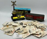 Photo showing a lot of vintage model train cars, railway crossing signal, and numerous small packaged train parts.
