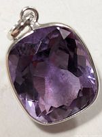 Front view of cushion-shaped faceted amethyst stone set in 10K gold pendant showing color and cut