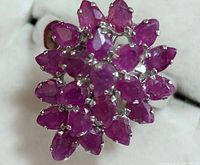 Close-up image showing pear-shaped and marquise-shaped ruby stones arranged in a flower cluster on a sterling silver ring.