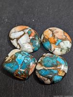 Four polished turquoise gemstones on black background showing color and matrix detail