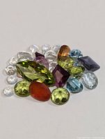 Pile of assorted faceted gemstones showing multiple colors and cuts.