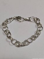 Full view of silver bracelet laid flat showing interlocking round links and lobster claw clasp