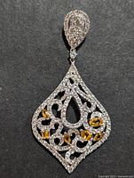 Front view of silver pendant showing citrine and clear cubic zirconia stones on black background