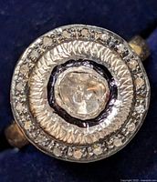 Close-up image of the ring face showing central diamond surrounded by textured silver and smaller diamonds