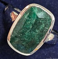 Close-up of the emerald stone set in silver bezel showing surface texture and color.