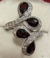 Top angle showing three pear-shaped garnet stones surrounded by cubic zirconia stones on silver band.