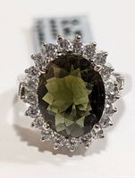 Close-up front view of ring showing the oval green tourmaline surrounded by clear stones.