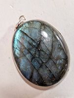 Close-up of oval labradorite pendant showing natural fractures and blue-green iridescence, set in simple silver bezel with bail.