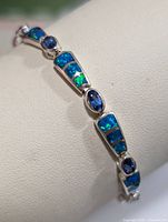 Close-up side view showing silver links with blue-green opalite inlays and blue oval stones.