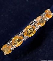 Close-up angled view showing the band and oval orange sapphire stones.