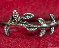 Close-up front view of silver ring featuring branch and leaf design