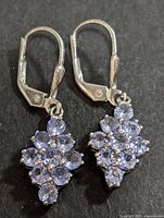 Front view of pair of silver lever-back drop earrings with clusters of round lavender tanzanites on black background