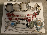 Assorted costume jewelry bracelets, necklaces, and brooches laid out on a white surface