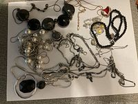 Photo showing a variety of costume jewelry items including multiple necklaces and bracelets arranged on a white surface.