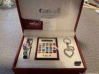 Photo of Curious Jewel Collection gift set including wristwatch, calculator, and heart-shaped keychain in box