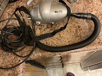 Silver Euro-Pro Shark vacuum cleaner with attached black flexible hose and shoulder belt, resting on countertop.