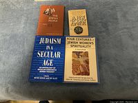 Top view of four Jewish-themed books placed on a gray surface.