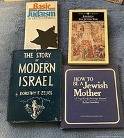 Top-down photo of four Jewish-themed books arranged on a blue surface: Basic Judaism, The Story of Modern Israel, Josephus The Jewish War, and How to Be a Jewish Mother.