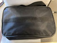 Closed black fabric survival kit bag showing the top and strap