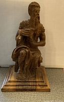 Frontal view of the wooden Moses statue showing detailed carving and polished finish on base.