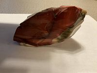 Side view of the red mineral stone sculpture showing polished surfaces and color variations.