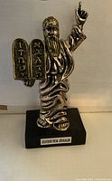 Front view of the silver Moses figurine showing him holding tablets with Hebrew inscriptions and raising one hand.