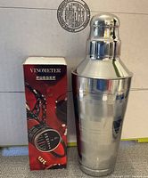 Vinometer box alongside stainless steel cocktail shaker.