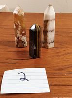 Three crystal towers displayed on a wooden surface - includes a banded brown/white tower, a Tigers Eye tower, and a translucent tower with druzy agate inclusions