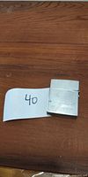 Top view of silver textured rectangular device placed on wood surface next to handwritten number tag '40'