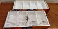 Four clear textured vintage Finnish glasses in original box displaying the glasses' shape and packaging.