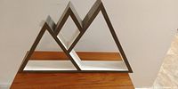Front view of wooden mountain-shaped wall shelf showing the triangular peak design and contrasting white base shelf.