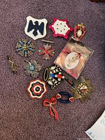 Full overhead view of all 14 brooches arranged on carpet to display design and color variety.