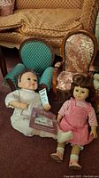 Photo of Farmer Girl doll sitting on floor next to small teal upholstered chair and small Victorian style floral patterned chair