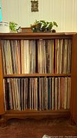 Two-shelf wooden cabinet filled edge-to-edge with vinyl LPs