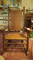 Front view of wooden rocking chair with woven wicker backrest and seat, showing overall condition and details.
