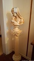 Full view of the mother and child ceramic statue atop decorative pedestal, showing height and placement in room corner.