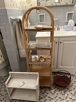 Photo showing two wicker shelving units and one wicker basket in tiled bathroom, shelving contains picture frames and decorative items not included
